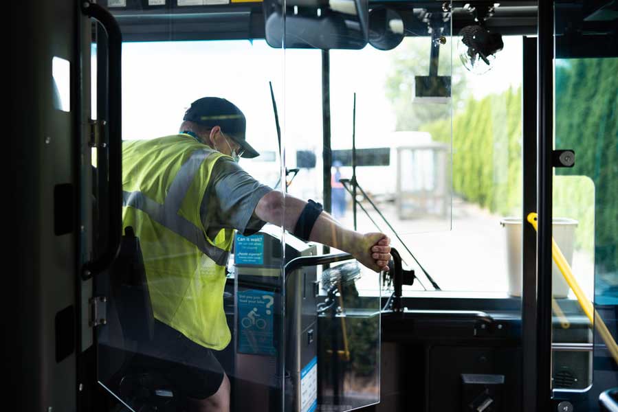 Masked bus driver opening plastic DriverGuard barrier