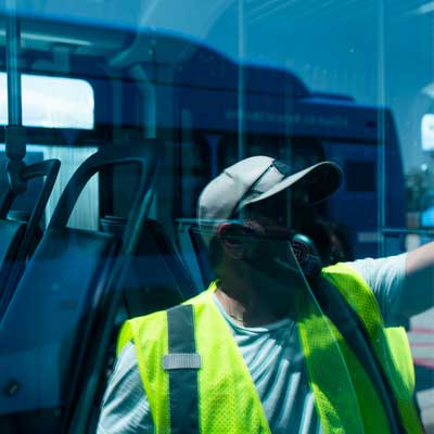 Masked worker washing bus windows
