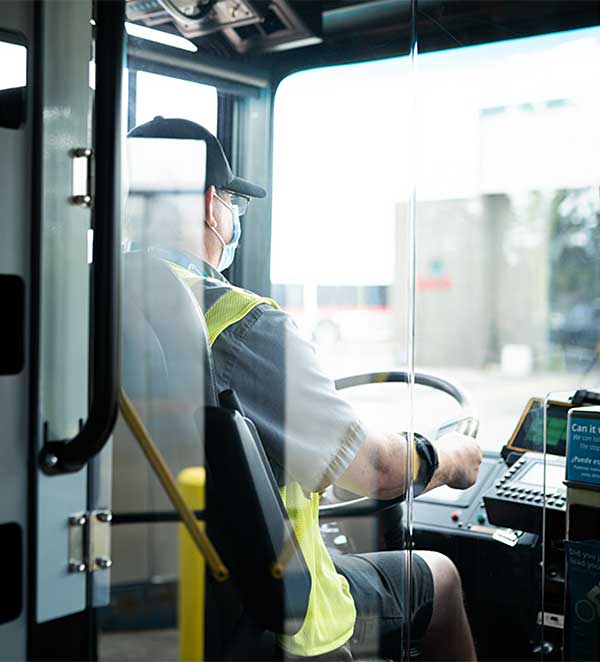 Bus driver looking ahead seen through plastic barrier